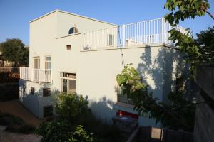a white building with a balcony on the side of it at Aviv Beautiful Villa, 5 BR, Golan Heights in Giv'at Yo'av