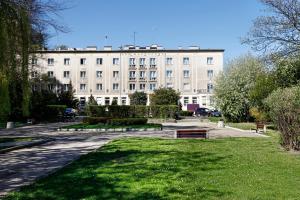 - un grand bâtiment blanc avec un parc en face dans l'établissement Hotel Dom Marynarza, à Gdynia