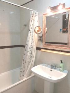 łazienka z umywalką, wanną i lustrem w obiekcie Apartamento Ossuna w mieście La Laguna