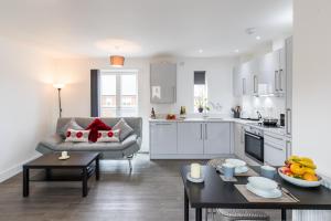 a kitchen and living room with a couch and a table at Abodebed Oval View Apartments in Hemel Hempstead