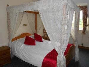 1 dormitorio con cama con dosel y almohadas rojas en The Glan Yr Afon Inn, en Holywell