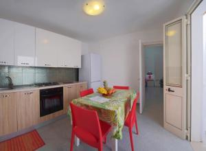 a kitchen with a table with red chairs and a kitchen with white cabinets at Eolo Casa Vacanze in Torre Lapillo