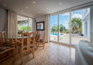 a dining room with a table and a view of a pool at Villa Can Massaueta in Sant Jordi