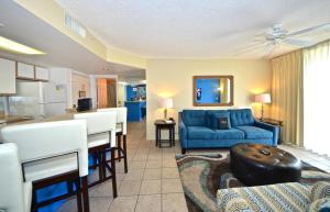 uma sala de estar com um sofá azul e uma cozinha em Sunrise Suites Big Kahuna Suite #202 em Key West