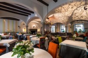 ベッラージョにあるHotel Florenceの白いテーブルと椅子、花のテーブルが並ぶレストラン