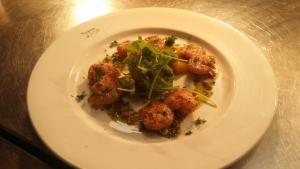 a plate of food with shrimp and greens on a table at The Elm Tree Inn in Wisbech