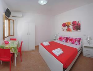 a white bedroom with a red and white bed and a table at Eolo Casa Vacanze in Torre Lapillo