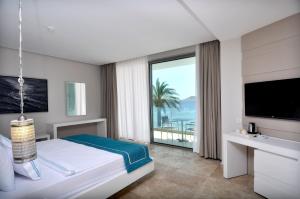 a hotel room with a bed and a large window at Luga Boutique Hotel & Beach in Ortakent
