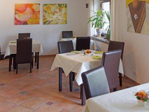 a dining room with tables and chairs and paintings at Hotel Garni Möwe in Tutzing