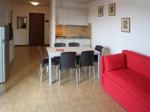 un soggiorno con tavolo, sedie e divano rosso di Giove a Lignano Sabbiadoro