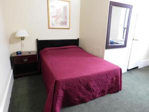 a bedroom with a bed with a purple blanket at Filmores Hotel in Toronto