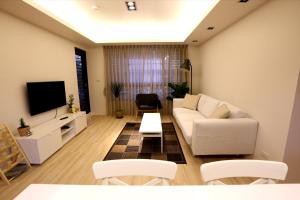 a living room with a white couch and a tv at Lienmei 月租房 in Taipei
