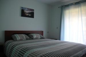 a bedroom with a bed with a striped comforter and a window at Encostas da Torre in Terras de Bouro