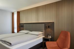 a bedroom with a bed and a chair at H4 Hotel Residenzschloss Bayreuth in Bayreuth