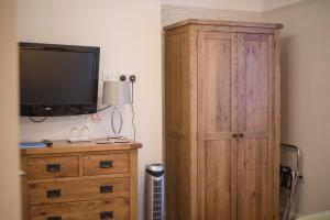 1 dormitorio con TV y tocador de madera en Birchleigh Guest House, en Grange-over-Sands