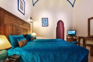 a bedroom with a blue bed and a tv at Riad & Spa Bahia Salam in Marrakesh