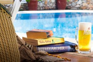 a glass of beer and books on a table next to a drink at Villa Maraki in Agia Paraskevi