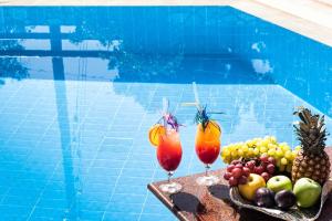 two cocktails and fruit on a tray next to a swimming pool at Villa Maraki in Agia Paraskevi