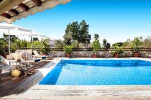 a swimming pool with chairs and an umbrella next to a patio at Villa Maraki in Agia Paraskevi
