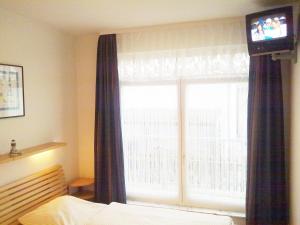 Schlafzimmer mit einem Bett und einem Fenster mit einem TV in der Unterkunft Villa Regina Maris Fewo Lachmöwe 70 m zum Strand in Bansin