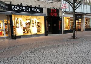 una calle adoquinada frente a una tienda de la ciudad en City Hotel, en Kristinehamn