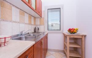 a kitchen with a sink and a bowl of fruit at Apartments Luka in Baška