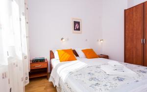 a bedroom with a bed with orange and yellow pillows at Apartments Luka in Baška