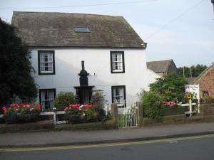 a white house with flowers in front of it at Stone House Farm in St Bees