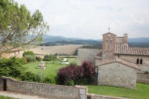 un antico edificio in pietra con una chiesa e un campo di La Pieve di San Martino a Colle Val D'Elsa