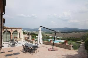 um pátio com uma mesa, um guarda-sol e uma piscina em La Pieve di San Martino em Colle Val D'Elsa