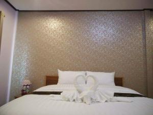 Una cama con dos cisnes hechos para parecer corazones en Mailuay Resort, en Buriram