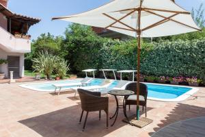 a patio with an umbrella and chairs and a pool at Villa Giovanna in Ragalna