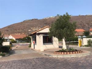 a small building with a tree in front of a hill at Whale Rock Gardens in Plettenberg Bay