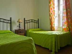 a bedroom with two beds with green sheets and a window at Casas Marin in Conil de la Frontera