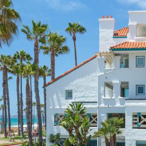 a white building with palm trees in front of the ocean at San Clemente Cove Resort in San Clemente