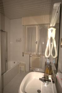 Baño blanco con bañera y lavamanos en Hotel Quercia Antica, en San Marino