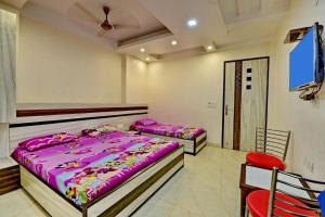 2 Betten in einem Schlafzimmer mit einem roten Stuhl in der Unterkunft Goel Residency in Neu-Delhi