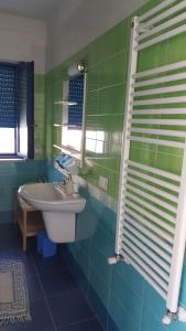 Baño verde con lavabo y espejo en Casa Vacanze MARESOLE, en Mattinata