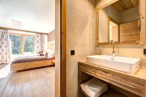 un bagno con un lavandino e un letto in una stanza di Rufana Lodge a Bürserberg