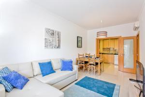 - un salon avec un canapé blanc et des oreillers bleus dans l'établissement Apartamento em Quinta da Barracuda, à Albufeira