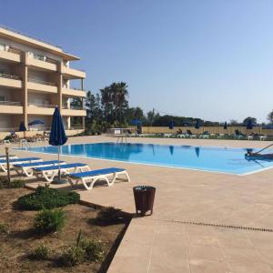 einen Pool mit Stühlen und Sonnenschirmen neben einem Gebäude in der Unterkunft Apartamento em Quinta da Barracuda in Albufeira