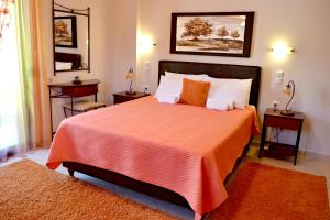 sypialnia z dużym łóżkiem z pomarańczową pościelą i poduszkami w obiekcie Anesis w mieście Janina