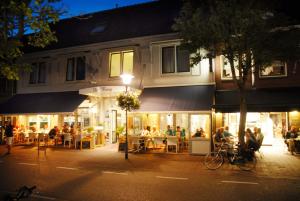 a group of people sitting outside a restaurant at night at Hotel de Burg in Domburg