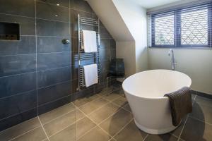 ein Badezimmer mit einer weißen Badewanne und einer Dusche in der Unterkunft The Chequers Inn in Beaconsfield