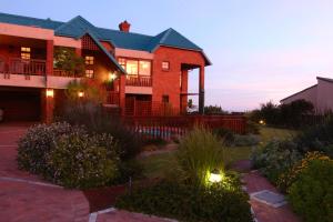 a large brick house with lights in a yard at Dolphin Dunes Guesthouse in Wilderness