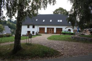 Un bâtiment blanc avec une voiture garée devant. dans l'établissement Ferienwohnung Friedrich, à Mildenau