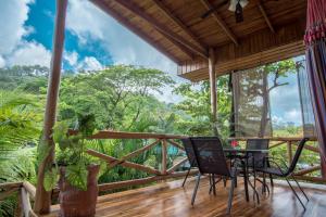 a balcony with a table and chairs and a view of the forest at Villas Solar in Santa Teresa Beach