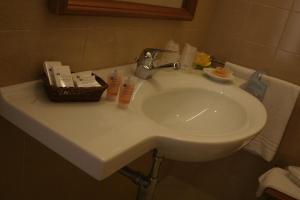 a bathroom sink with a basket of cosmetics on it at Hotel Centro di Spiritualità Padre Pio in San Giovanni Rotondo
