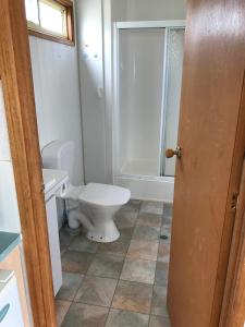 a bathroom with a white toilet and a shower at Prom Central Caravan Park in Foster