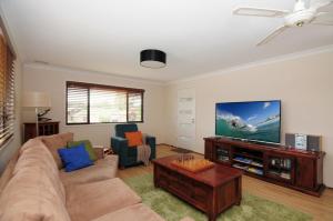 a living room with a couch and a flat screen tv at Sandy Feet Getaway in Sanctuary Point